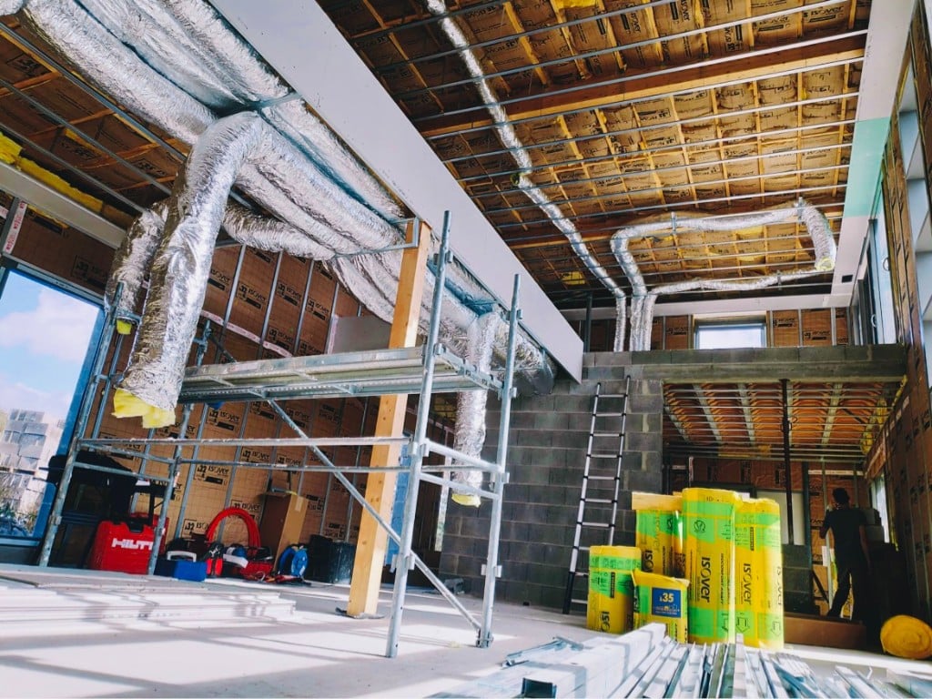 Installation d'un système de climatisation gainable : réseau de gaines isolées dans un bâtiment en rénovation