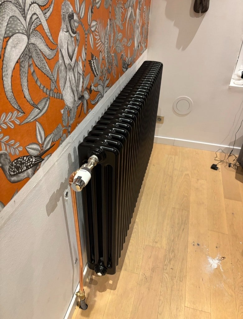 Tête thermostatique blanche sur radiateur à colonnes noires — réglage pièce par pièce par Hecker & Frères Énergie (HFE) à Lille